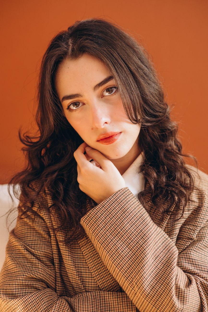 Portrait of a woman in a checked coat against a terracotta wall